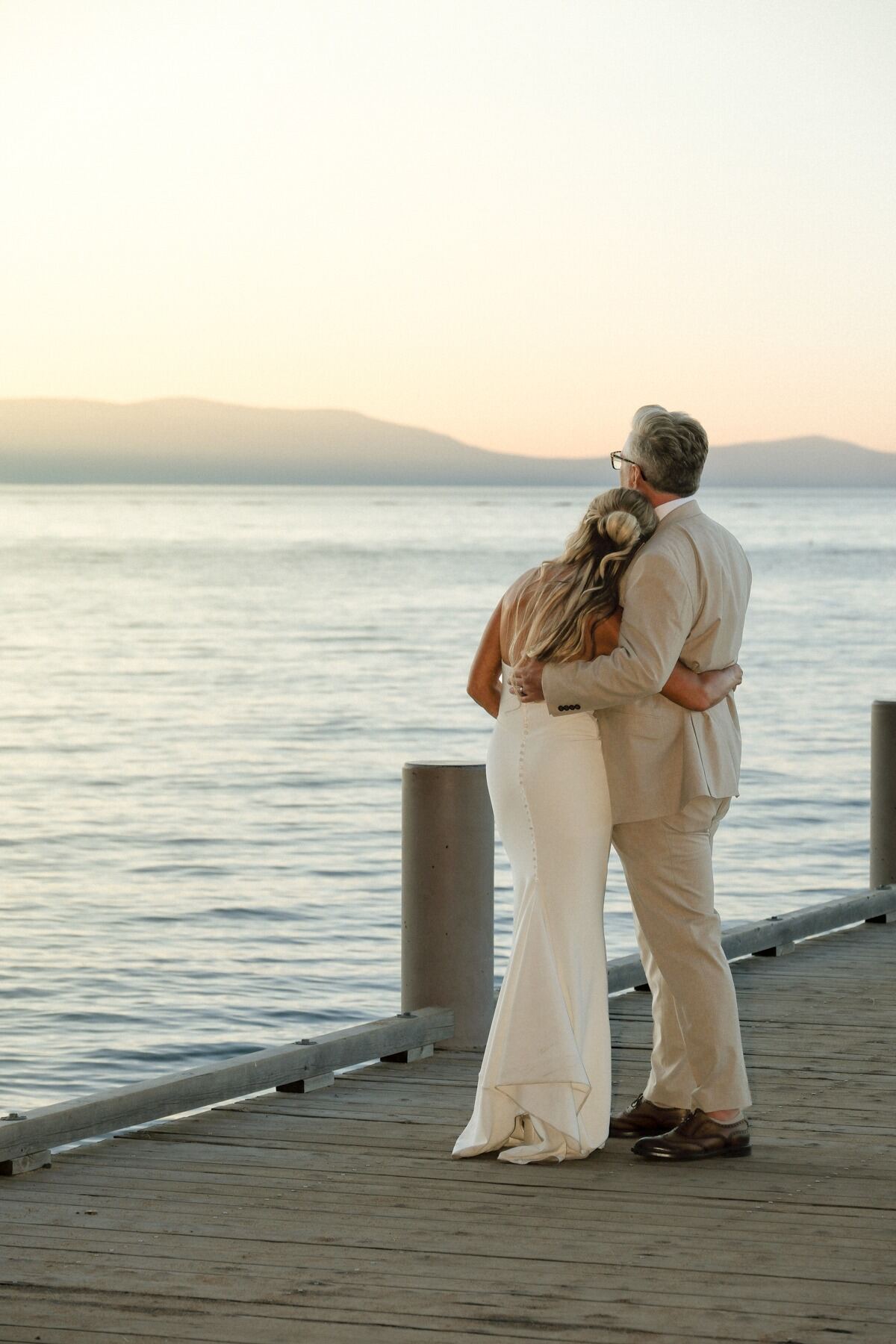 Newly married couple embracing while looking across Lake Tahoe