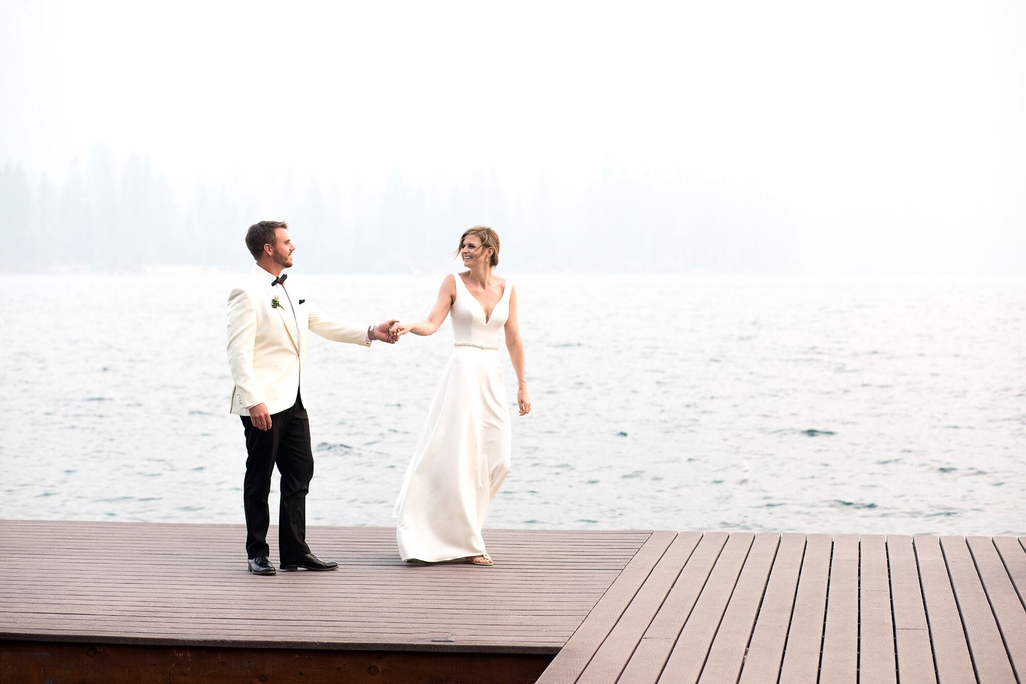 Wedding couple holding hands beside the lake
