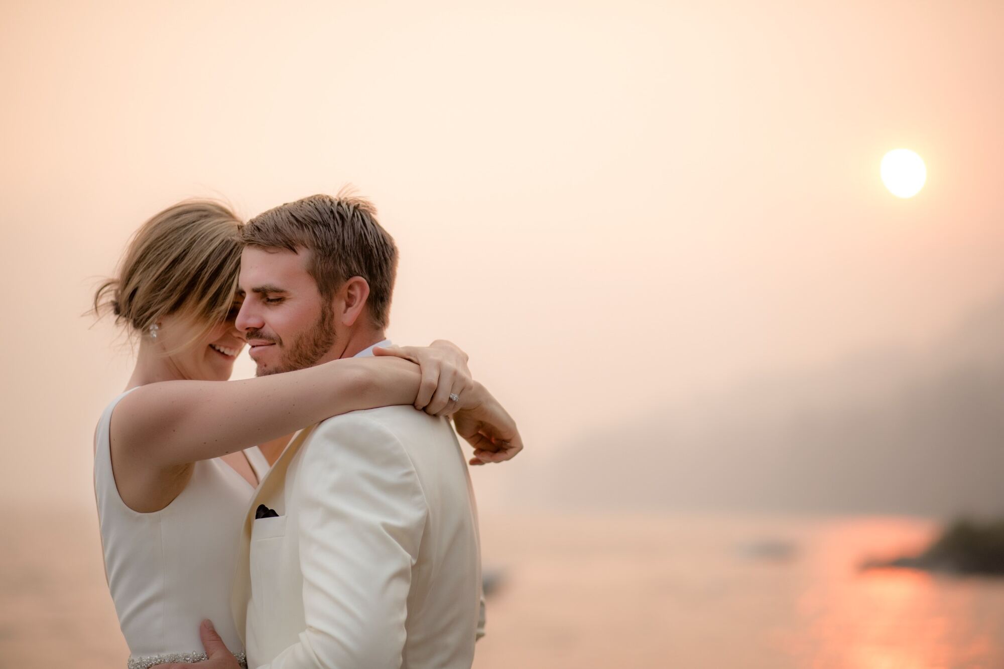 Wedding couple embracing beside Lake Tahoe at sunset